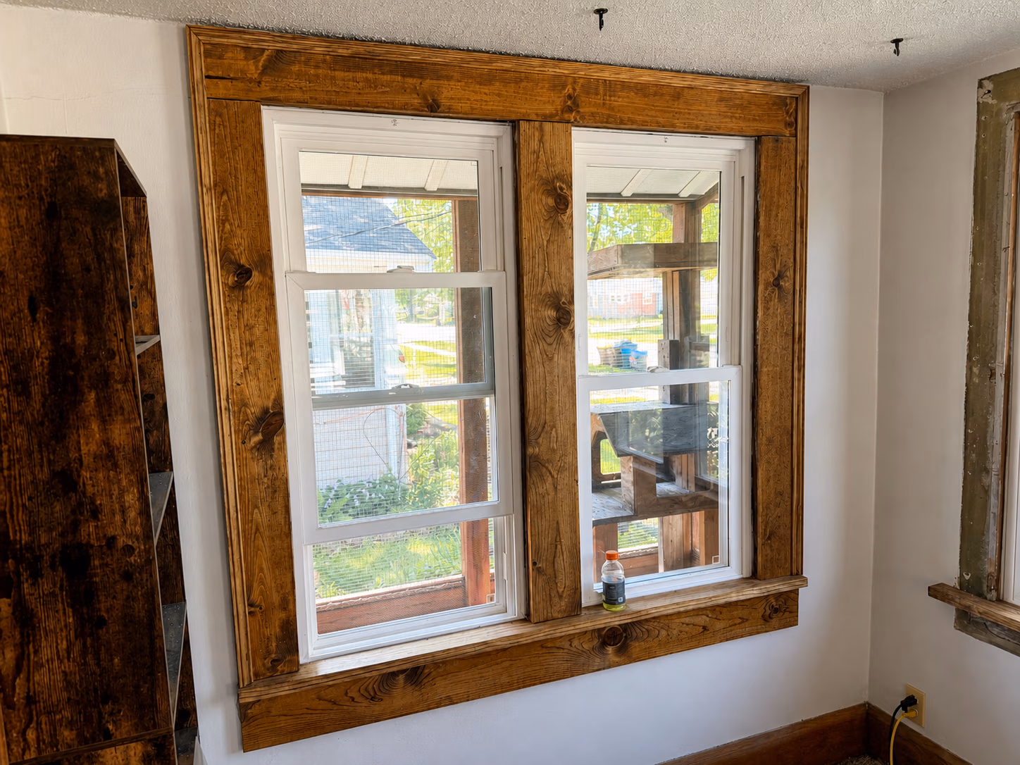 Newly installed three-panel sliding window in construction wall covered with house wrap and plywood on lower section.