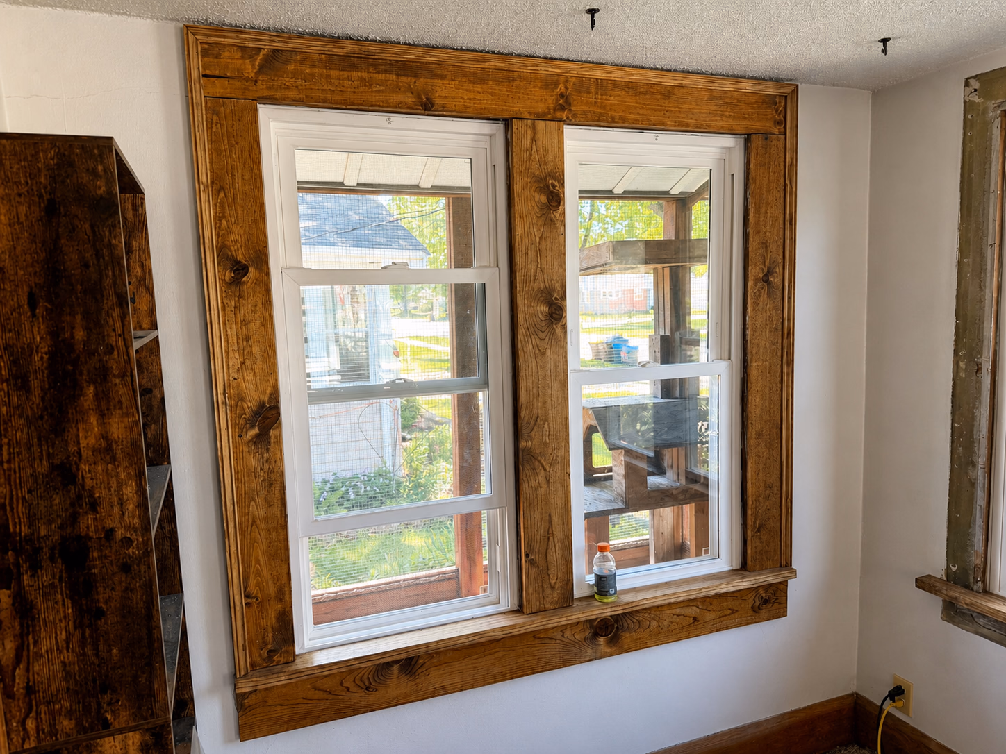 Newly installed three-panel sliding window in construction wall covered with house wrap and plywood on lower section.